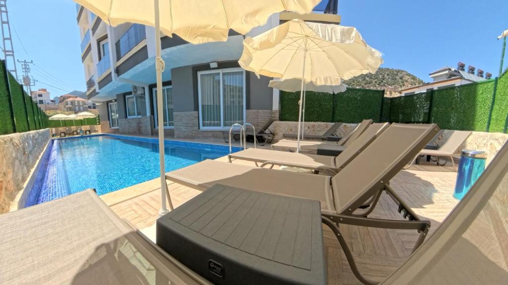 a swimming pool with two chairs and an umbrella at Hillfort Suites Apart Otel in Demre