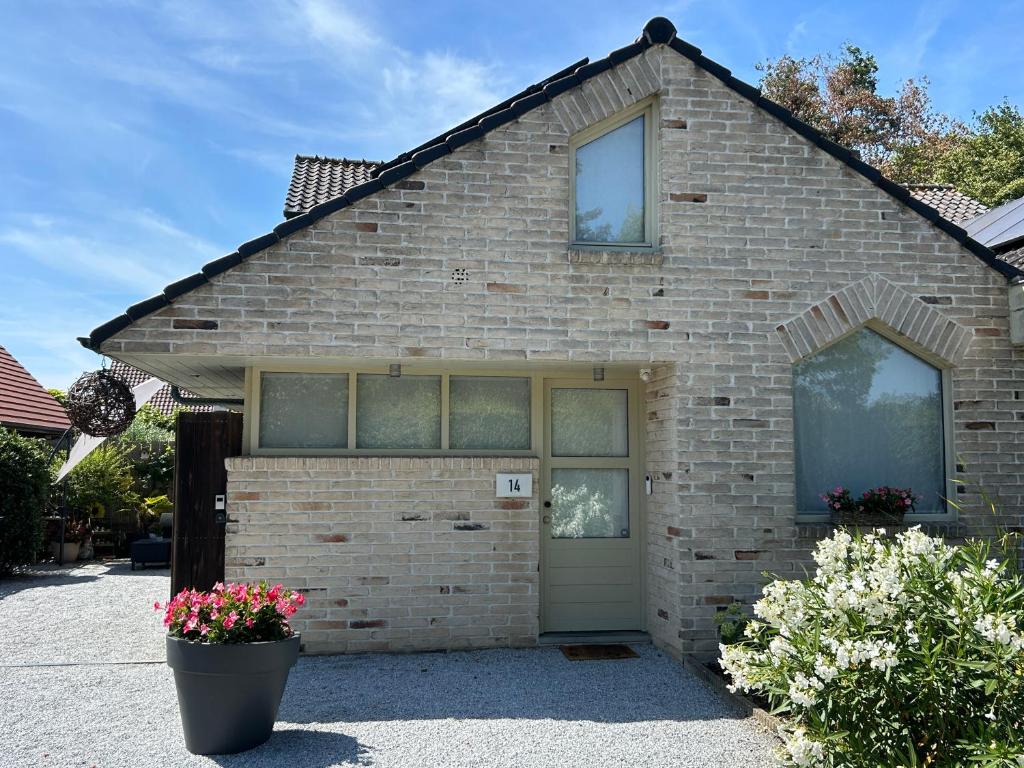 a brick house with a door and flowers in front at Toezens in Ingelmunster