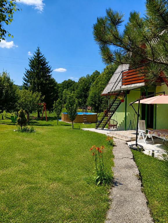 a yard with a house with a bench and an umbrella at Vila Jezerce Zlatibor Zbojštica in Užice