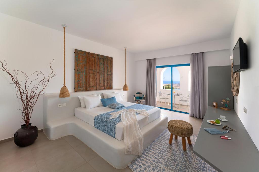 una camera da letto bianca con un grande letto e una finestra di Lindos Portes Suites - Adults Only a Líndos