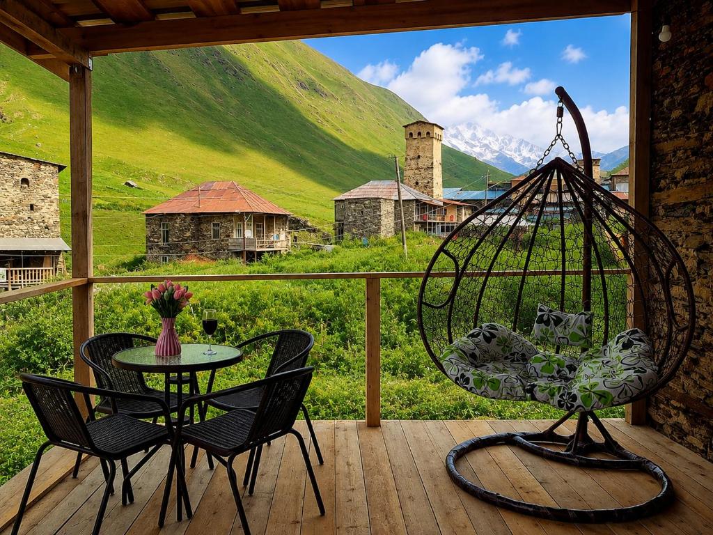 a patio with a table and chairs and a view of a mountain at Chvibiani Guesthouse & Bar in Ushguli