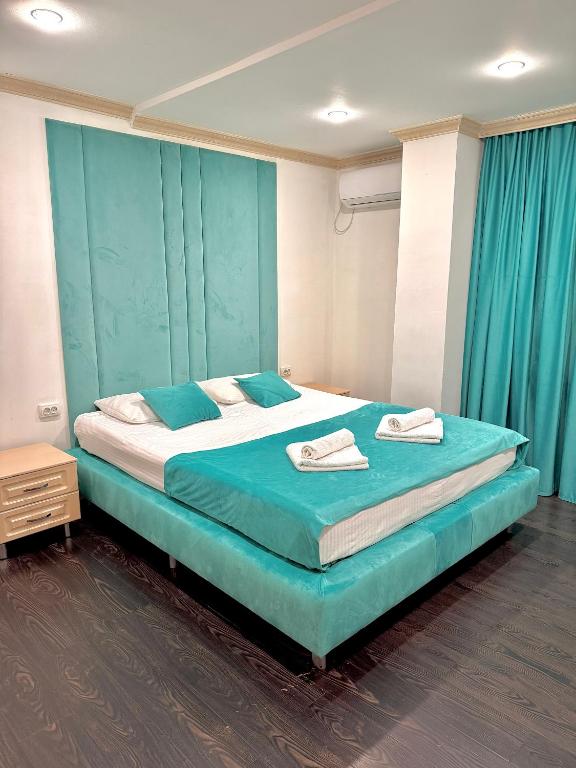 a bedroom with a large bed with a blue headboard at Djasmines Hotel Astana in Astana