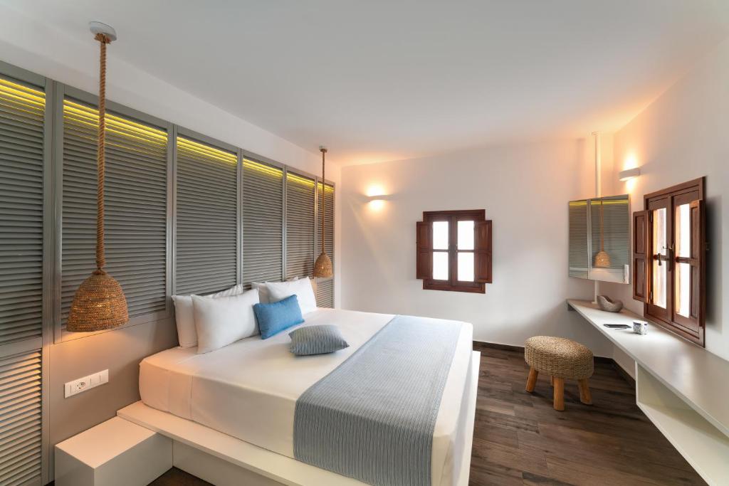 a bedroom with a large white bed and a desk at Lindos Del Mar Suites - Adults Only in Lindos