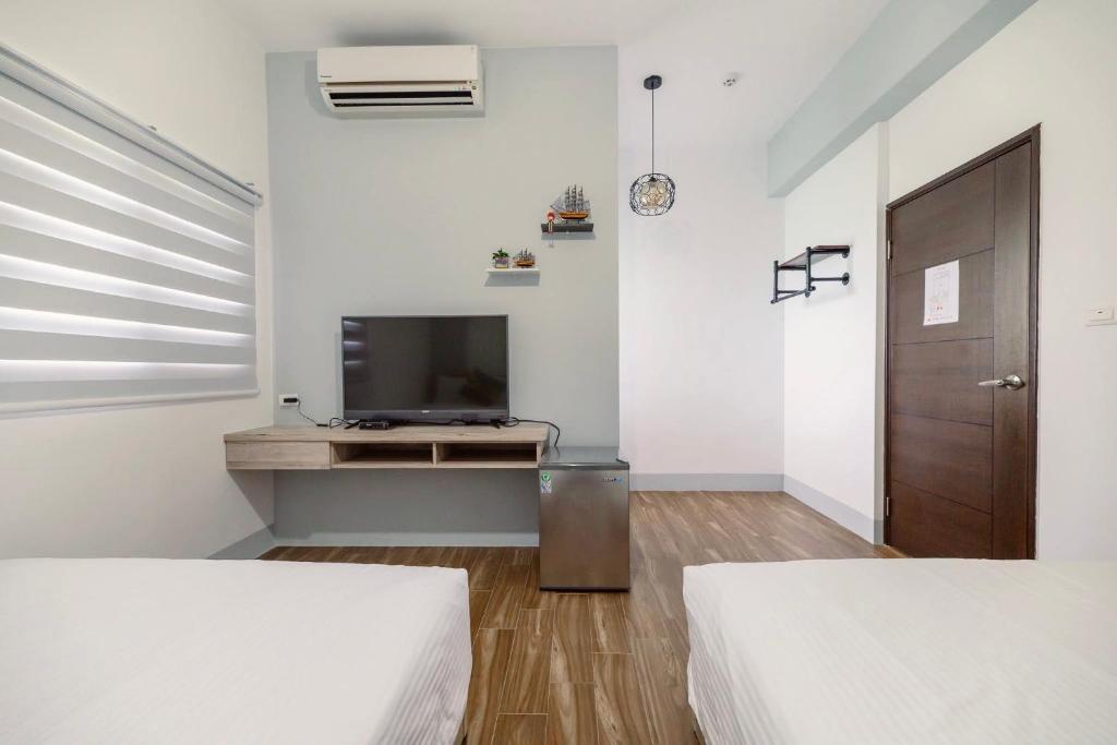 a white room with two beds and a television at 澎湖青翠民宿 in Magong