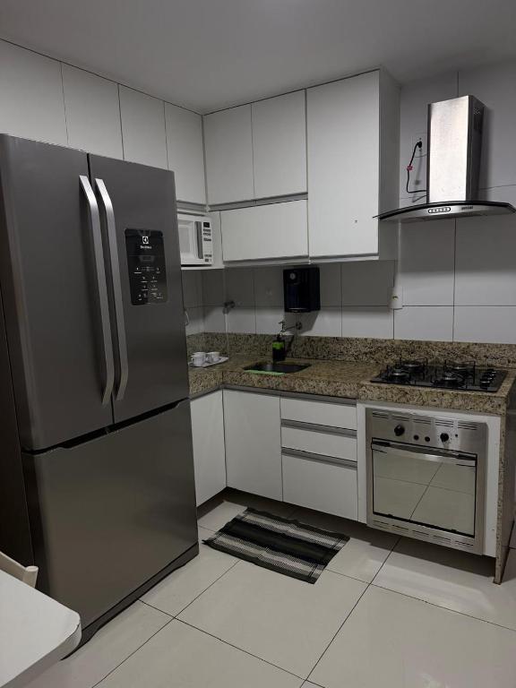 a kitchen with stainless steel appliances and white cabinets at Ed forte da Praia in Guarapari