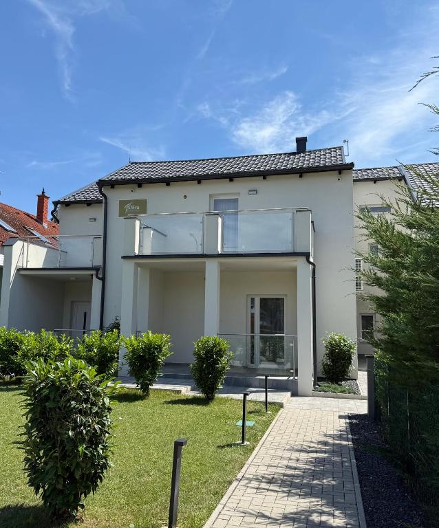 a white house with a large glass window at Oliva Apartman in Bük