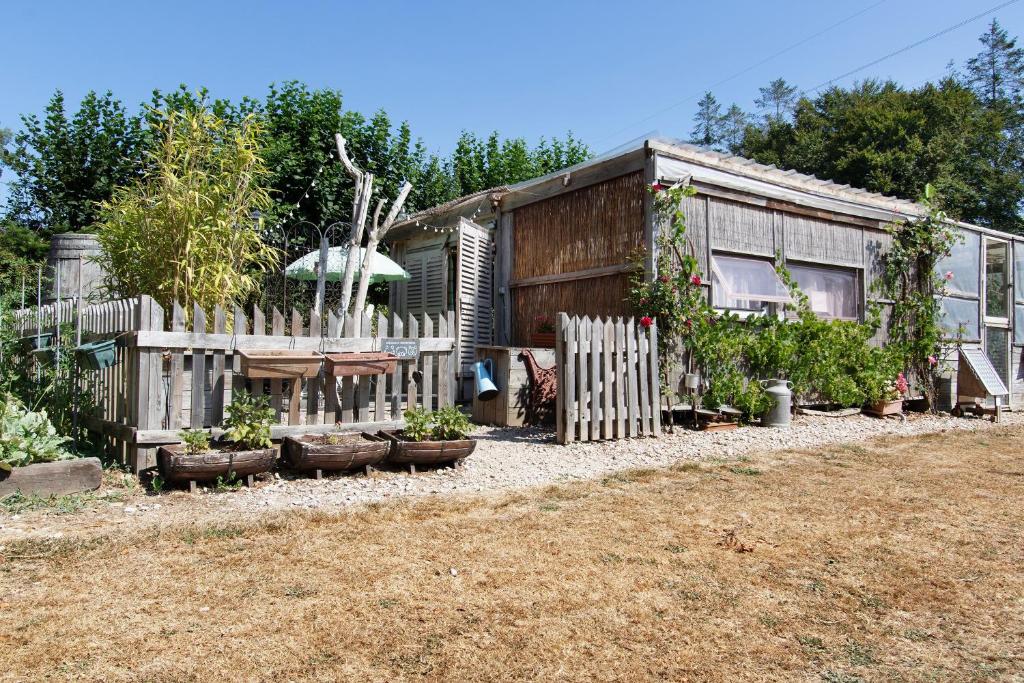 a house with a fence and plants in a yard at Caravane au jardin in Brix