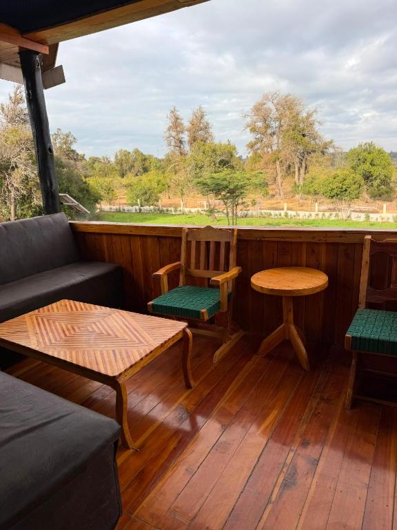 a porch with a couch and a table and chairs at EarthShip Log Cabin, Timau in Nanyuki