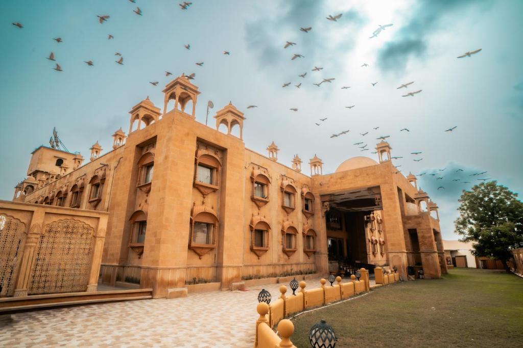 a large building with birds flying in the sky at Chokhi Dhani The Palace Hotel in Jaisalmer