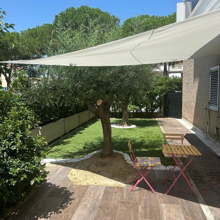 a patio with a table and a white umbrella at Mare e Tulipani in Porto San Giorgio