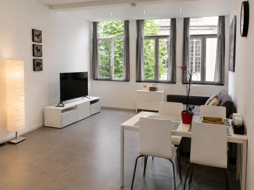 a living room with a table and a television at Apart'Hotel Liège City Centre in Liège