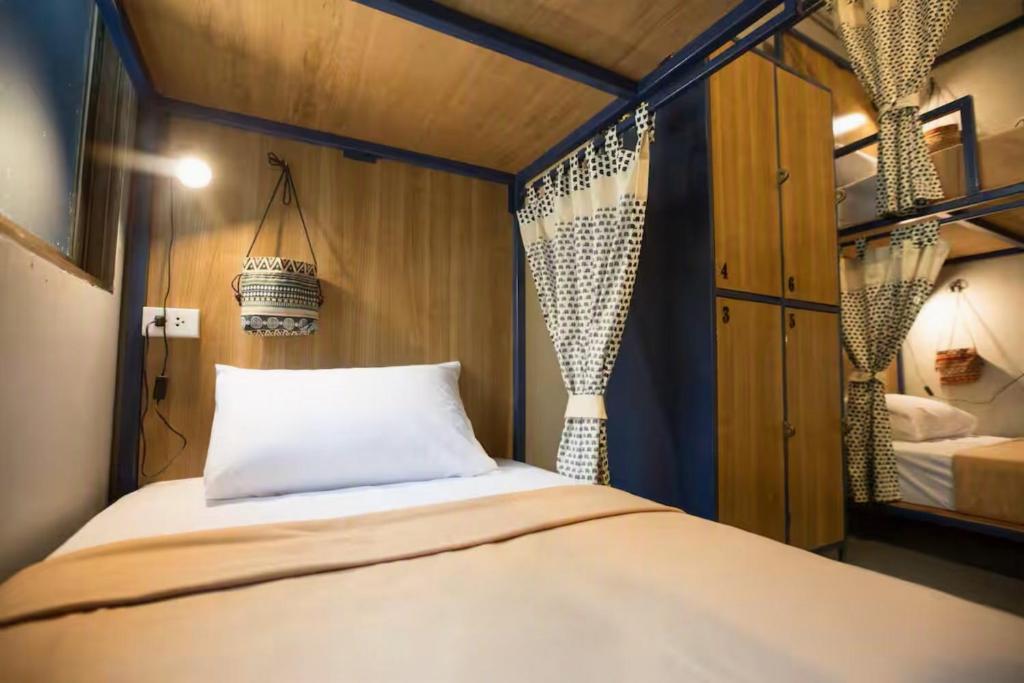 a small bedroom with a bed and a mirror at Arawana Hostel Silom in Bangkok