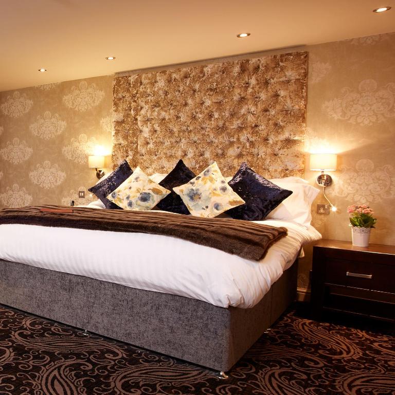 a bedroom with a large bed with blue and white pillows at Winteringham Fields in Winteringham