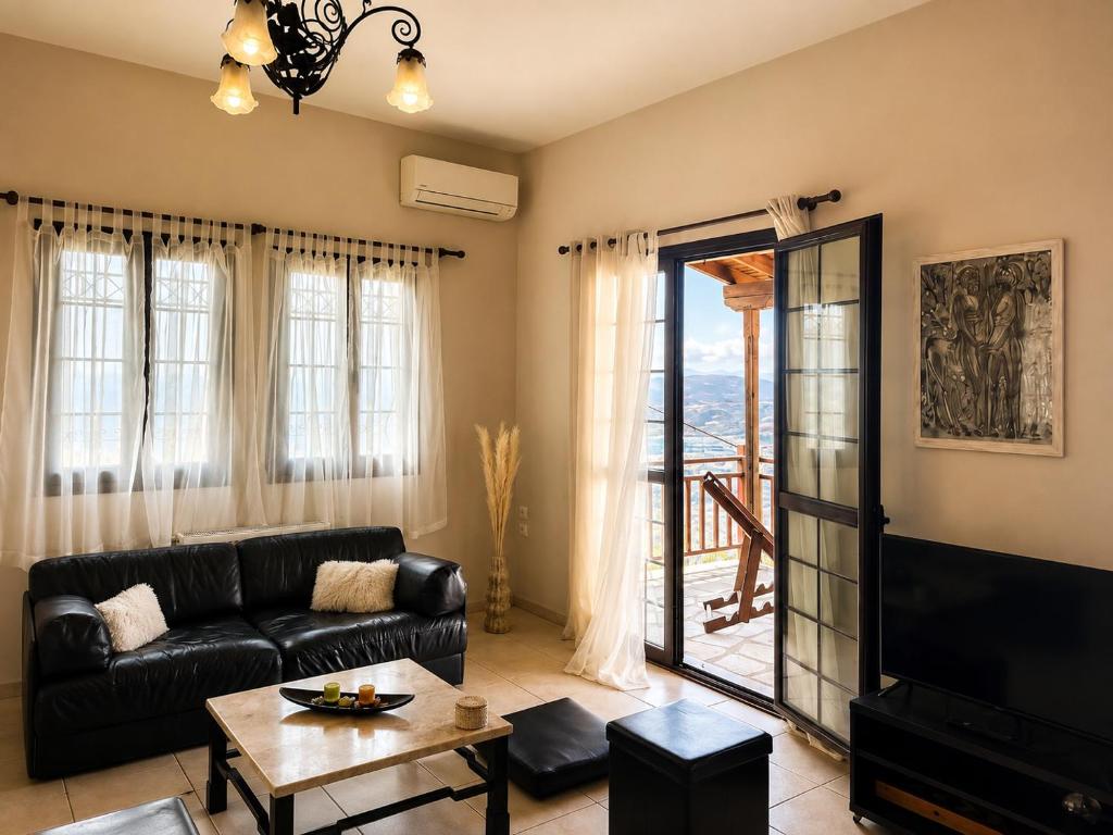 a living room with a black leather couch and a tv at Stagiates House in Stagiates