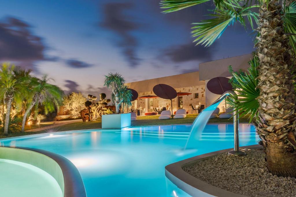 a swimming pool with a palm tree in front of a building at Zurafa Resort in Terrauzza