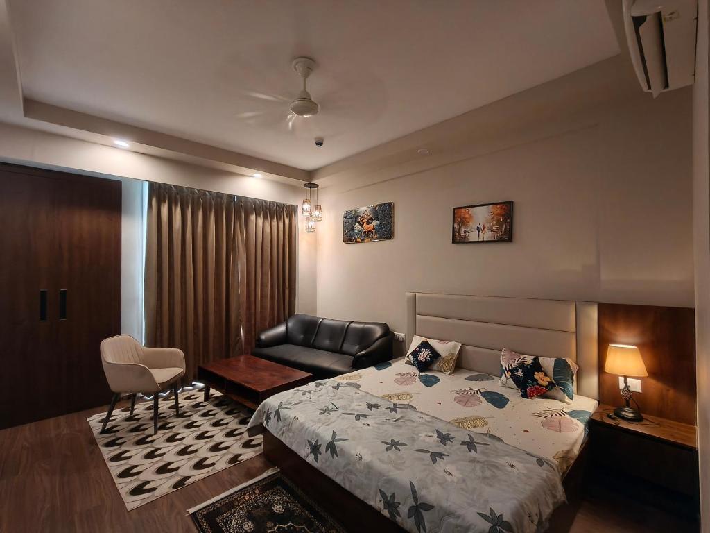 a bedroom with a bed and a chair and a couch at Sunlit Omaxe ITC, Greater Noida in Greater Noida