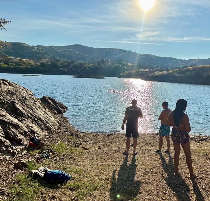 three people standing on the shore of a lake at Casa Vilariça in Alfândega da Fé