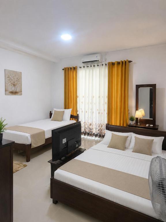 a hotel room with two beds and a television at The Kandyan Nest in Kundasale