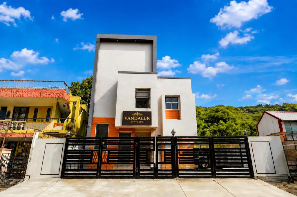 a white building with a black fence in front of it at Vandalur Stay's Inn in Vandalūr