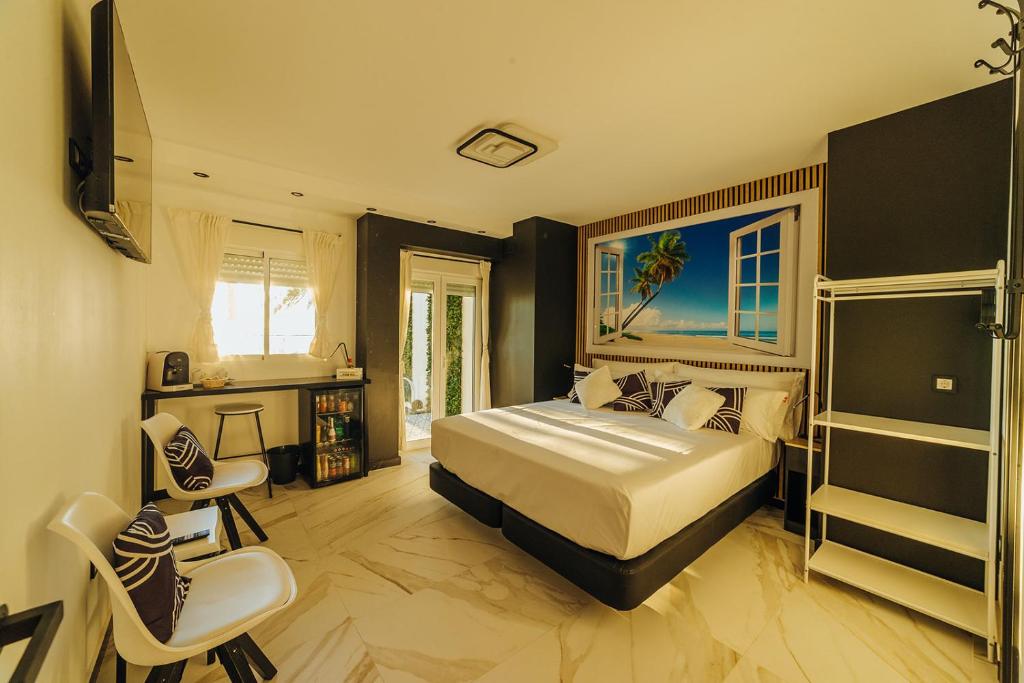 a bedroom with a bed and a desk and chairs at HOSTAL LUXURY NIT I DIA in Altea