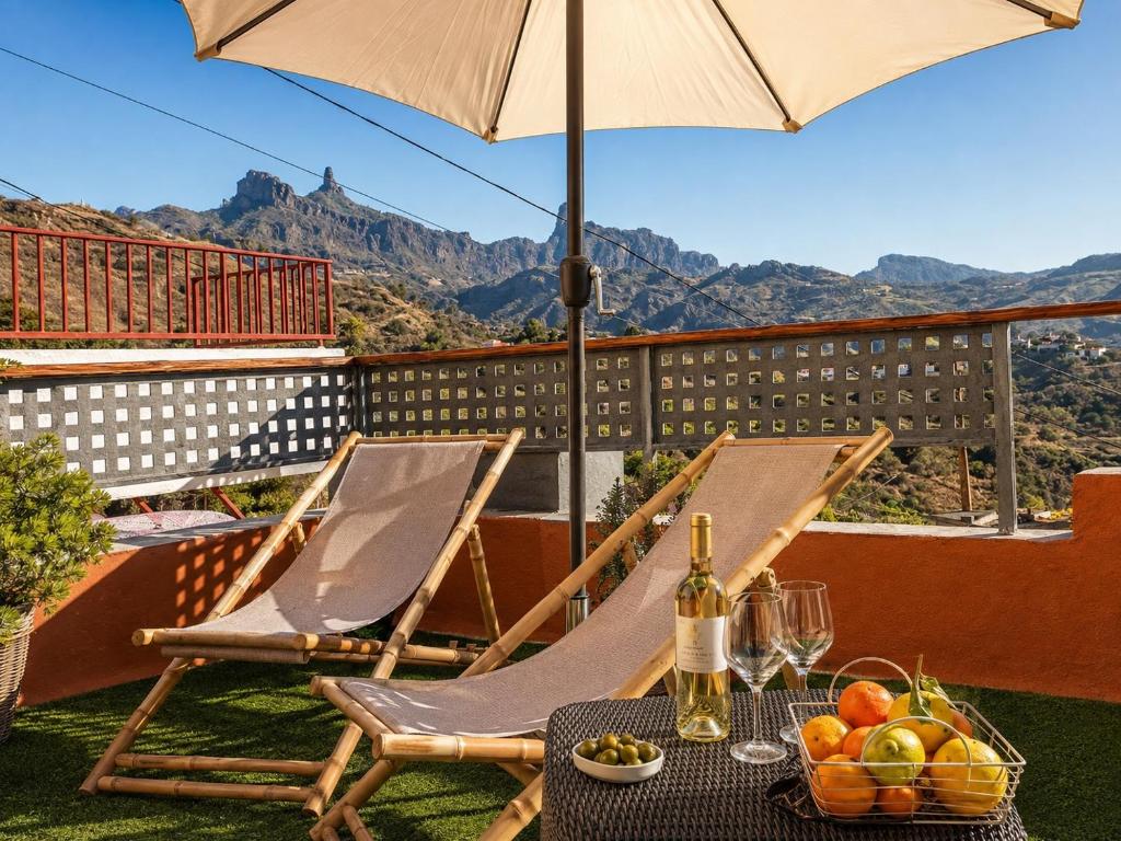 a table and chairs on a balcony with an umbrella at Casa Ada con Terraza Panorámica al Roque Bentayga by Canarias Prime Homes in Tejeda