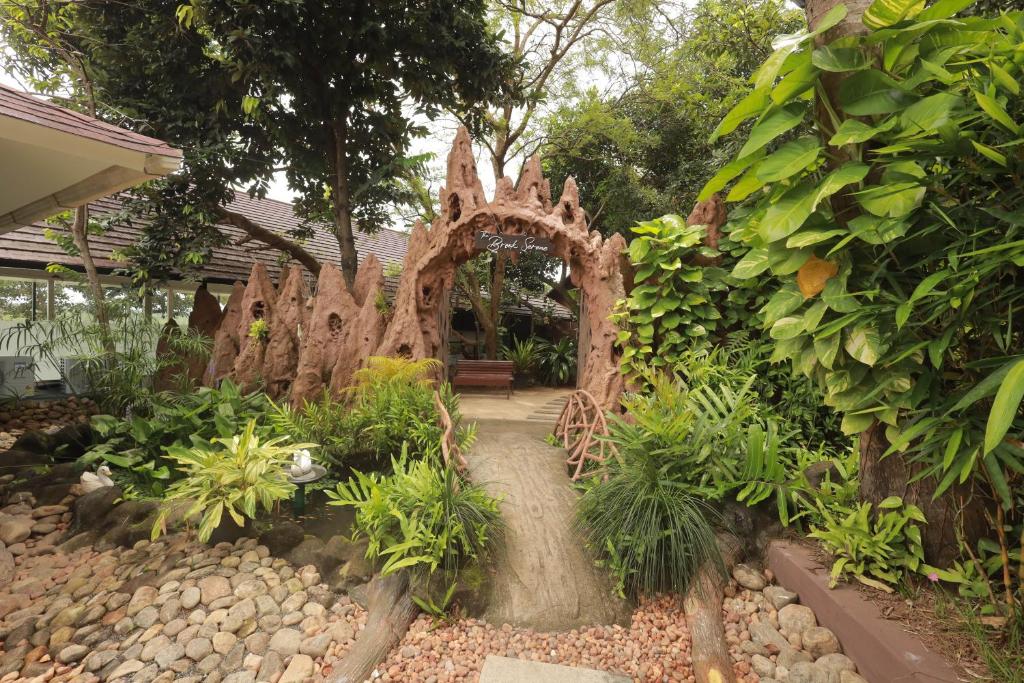 a garden with a wooden archway in a yard at The Brook Serene - A Nature Themed Boutique Resort, Kollam in Kottiyam