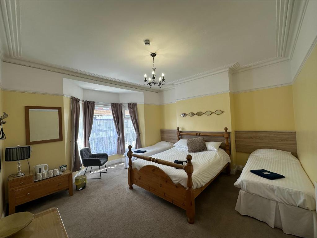 a bedroom with two beds and a chair and a chandelier at The Beacon Hotel in Redcar