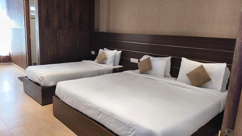 a hotel room with two beds with white sheets at Matha Residency Munnar in Suryanelli