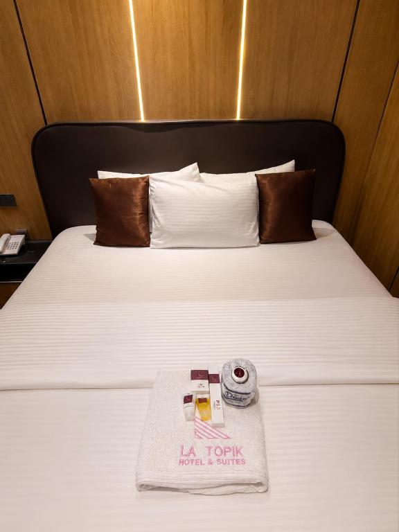 a hotel room with a white bed with a towel on it at La Topik Hotel & Suites in Otta