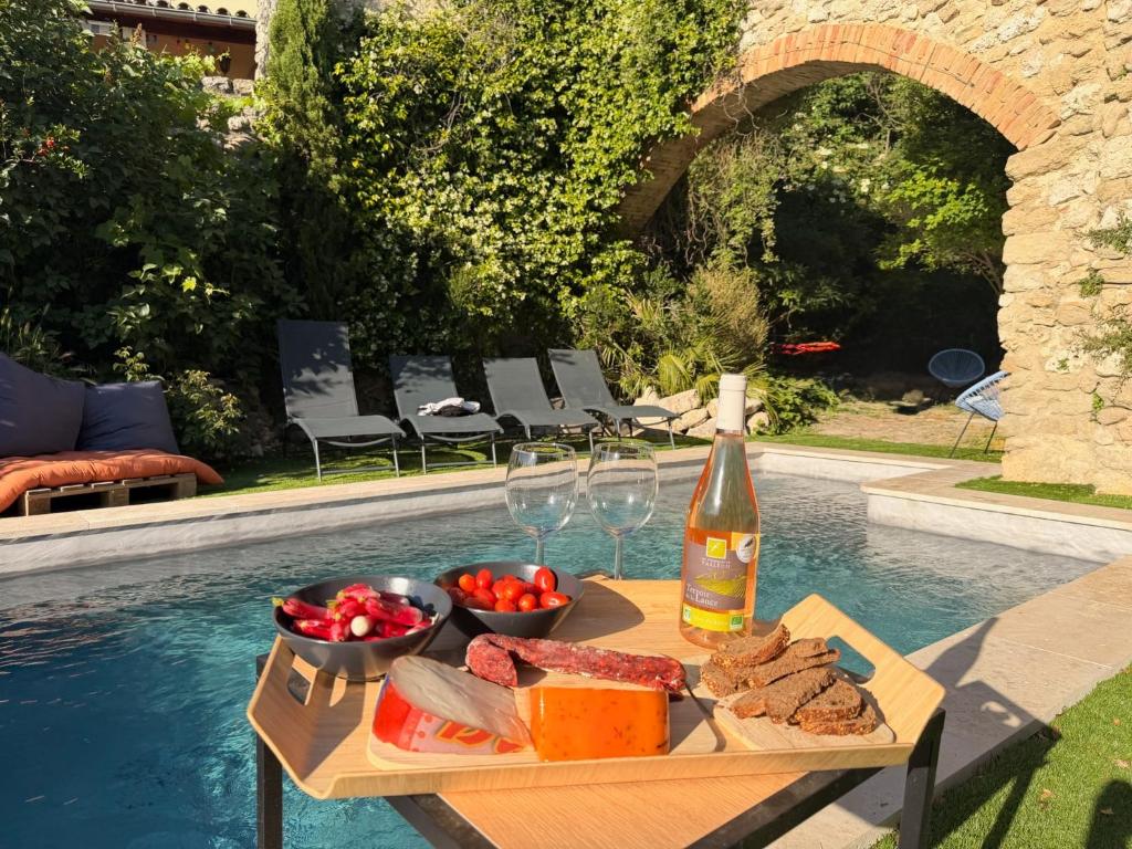 a table with a bottle of wine and food next to a pool at Le jardin de Grignan in Réauville