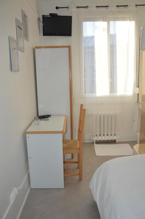 a room with a bed and a desk and a chair at Hôtel De Normandie in Amiens