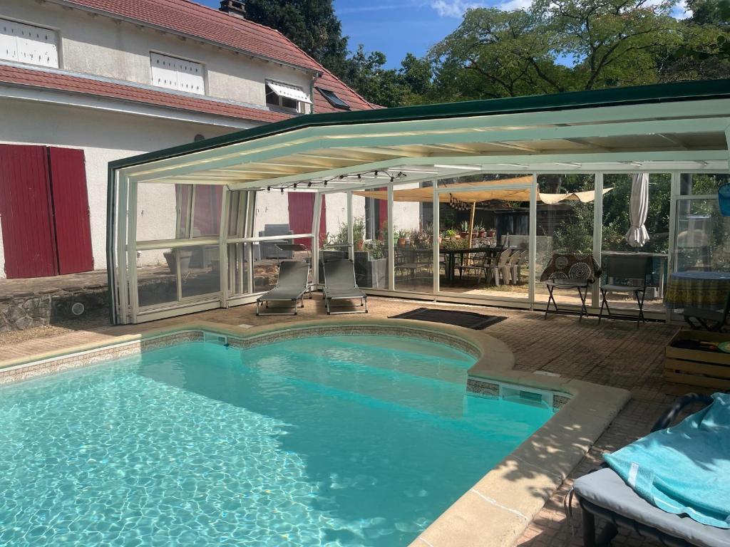 a swimming pool with an umbrella and a patio at le Refuge de Pia in Piégut-Pluviers