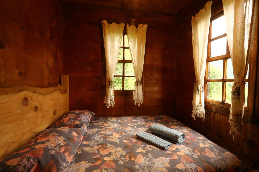 a bed in a room with two windows at Anka Köy Evi in Çamlıhemşin