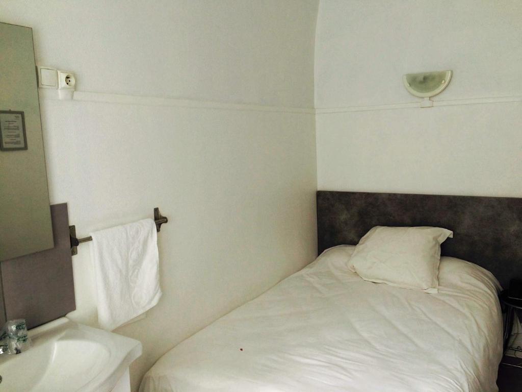 a small bedroom with a bed and a sink at Hôtel De Normandie in Amiens