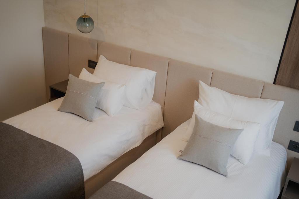 zwei Betten in einem Hotelzimmer mit weißen Kissen in der Unterkunft Sobe Vincentius in Metković