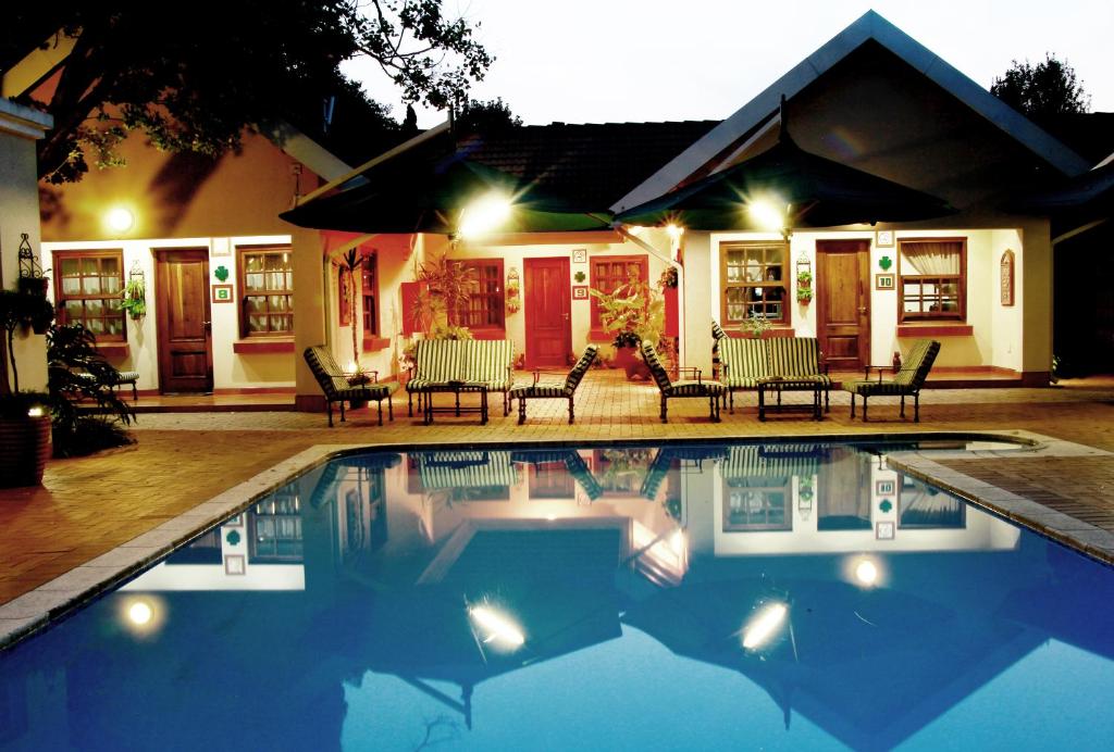 una piscina davanti a una casa di notte di Waterkloof Guest House a Pretoria