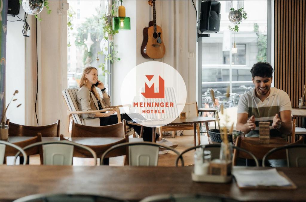 a man and a woman sitting at a table in a restaurant at MEININGER Hotel Copenhagen in Copenhagen