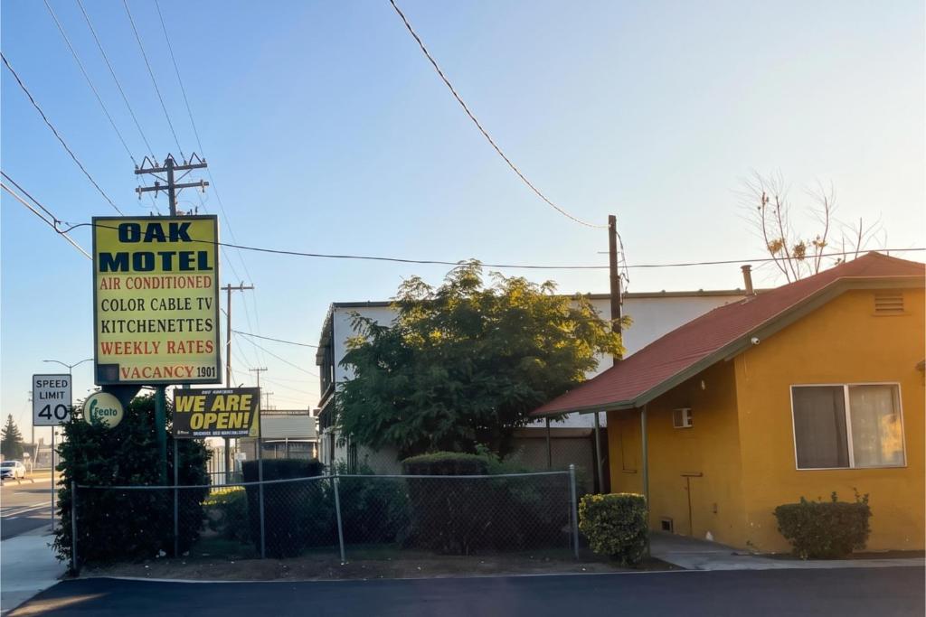 a sign for a car motel next to a building at Oak Motel Modesto CA in Modesto