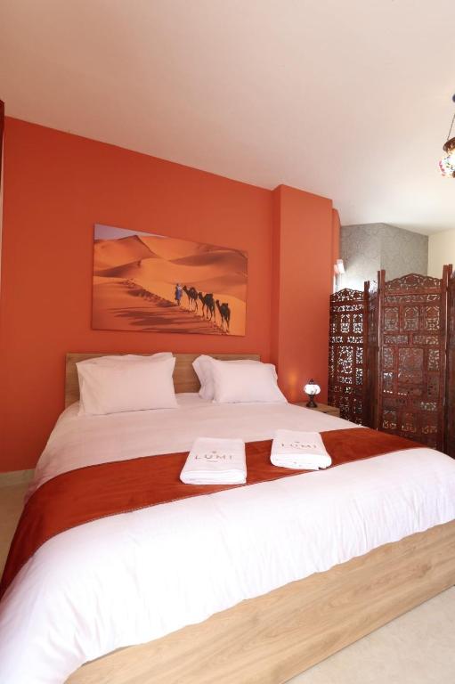a bedroom with a large bed with orange walls at LUMI amchit in Al Qarfī