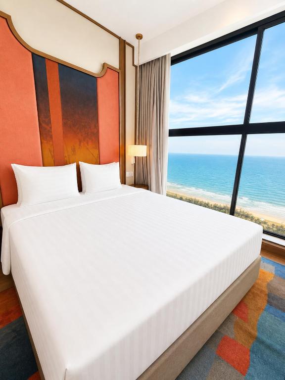 a bedroom with a bed with a view of the ocean at Thanh Son Apartment Mui Ne Beachfront in Ấp Thiẹn Ái