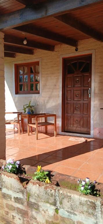 a porch of a house with a wooden door at Cabaña Familiar con arroyo sobre Ruta 12 II in Santa Ana