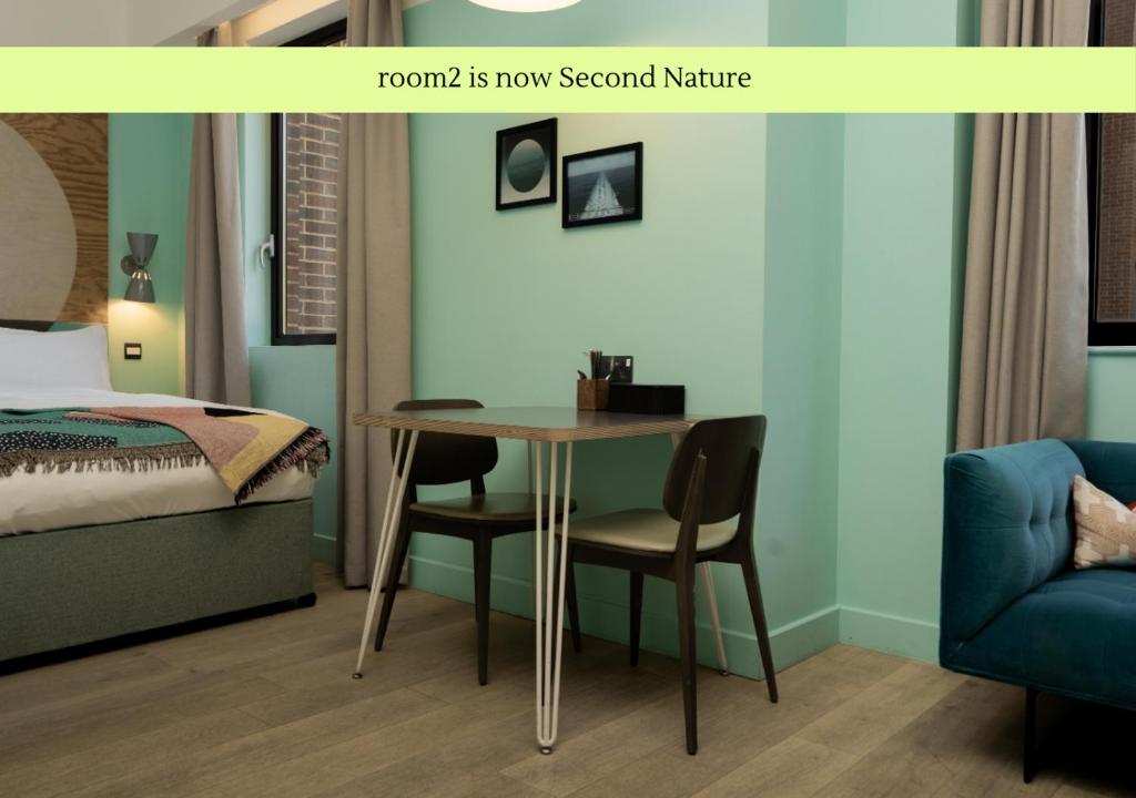 a bedroom with a table and a bed and a room with a bed at Second Nature Southampton in Southampton