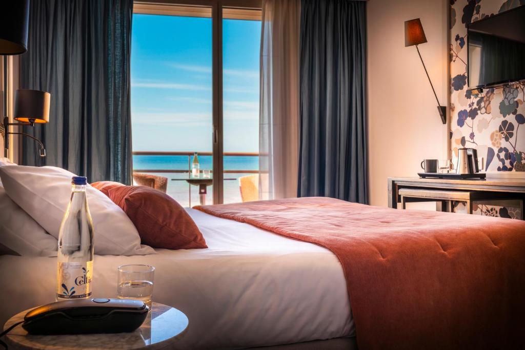 a hotel room with a bed with a view of the ocean at Hotel & Spa Les Roches Noires in Les Sables-d'Olonne