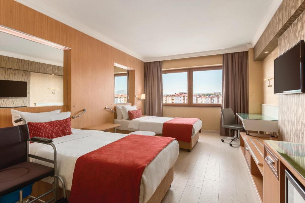 a hotel room with two beds and a television at Ramada Usak in Uşak