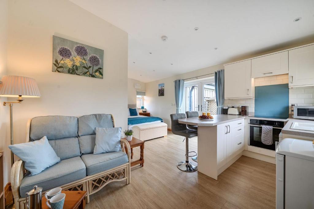a living room with a couch and a kitchen at Ashclose Lodge Annexe in Sherborne