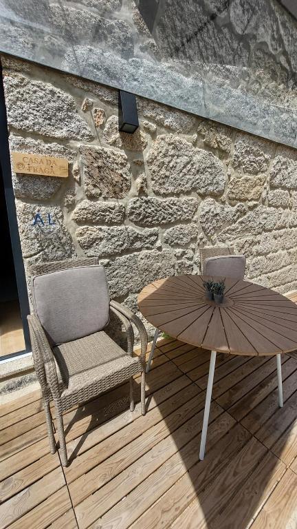 a table and a chair and an umbrella next to a stone wall at Casa da Fraga in Soajo