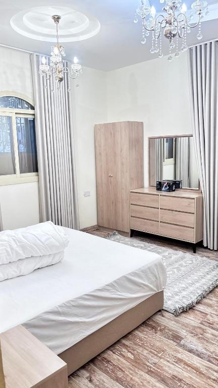 a bedroom with a large bed and a chandelier at شقة استديو in Al Baha