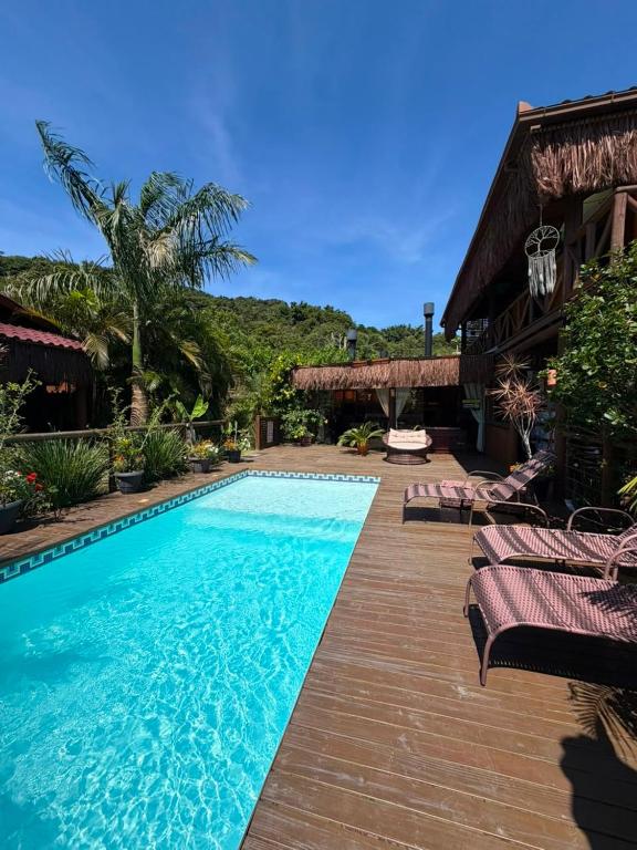 a swimming pool with chaise lounges next to a resort at Pousada Rosa Astral ॐ in Praia do Rosa
