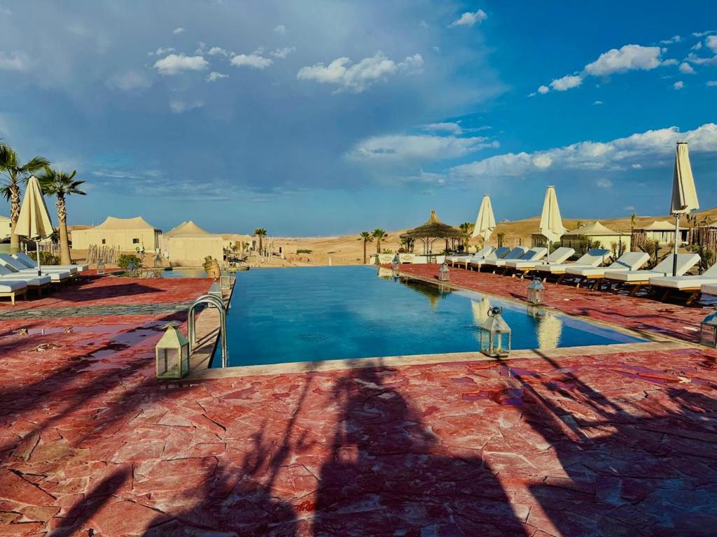a resort swimming pool with chairs and umbrellas at Yes We Camp Agafay Luxury Khaïma & Restaurant - Spa in El Karia