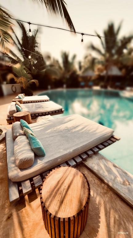 a wooden cutting board next to a swimming pool at Zen Boutique Retreat & Resort in Jambiani